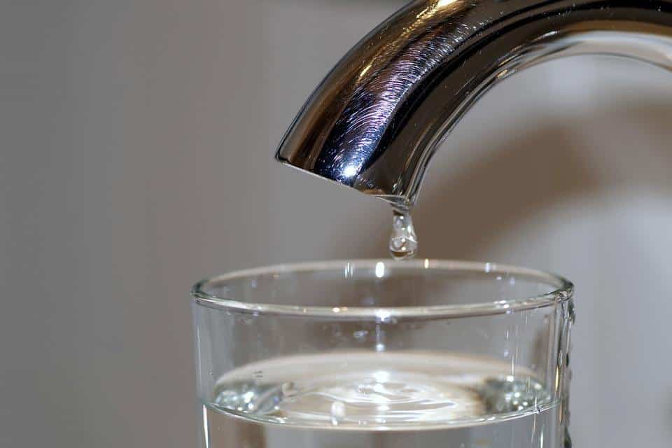 water faucet with a full glass of water