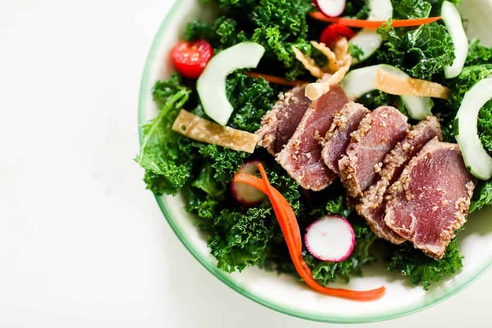 kale salad with meat, radishes, cucumber, and cherry tomatoes